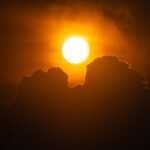 A vibrant sunset with silhouetted clouds creates a dramatic and warm scene in the sky.