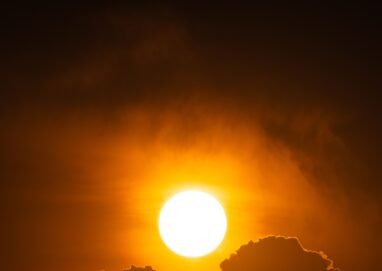 A vibrant sunset with silhouetted clouds creates a dramatic and warm scene in the sky.