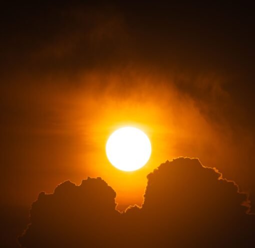 A vibrant sunset with silhouetted clouds creates a dramatic and warm scene in the sky.