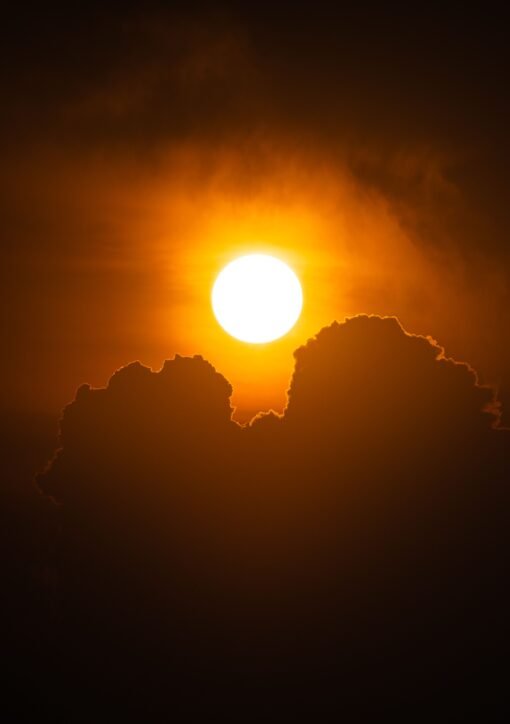 A vibrant sunset with silhouetted clouds creates a dramatic and warm scene in the sky.