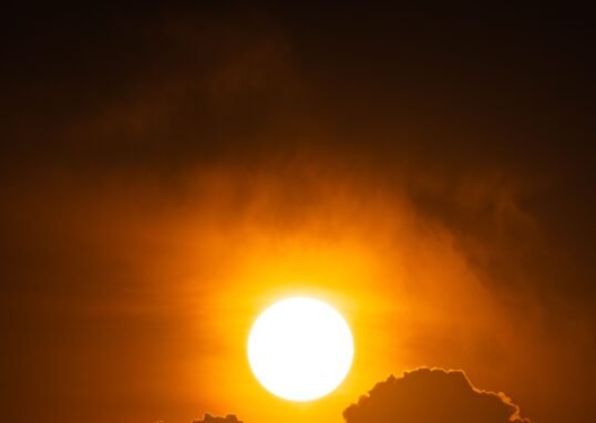 A vibrant sunset with silhouetted clouds creates a dramatic and warm scene in the sky.