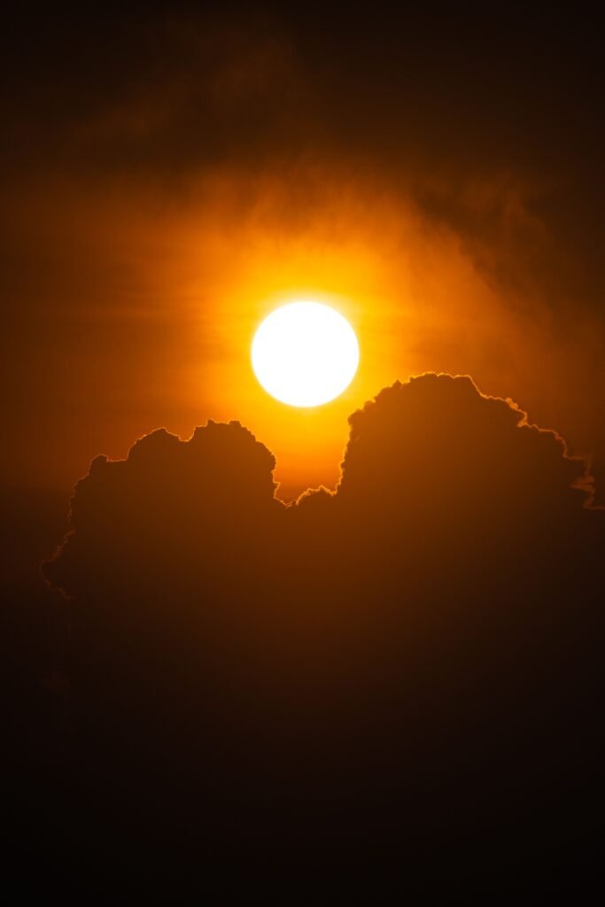 A vibrant sunset with silhouetted clouds creates a dramatic and warm scene in the sky.