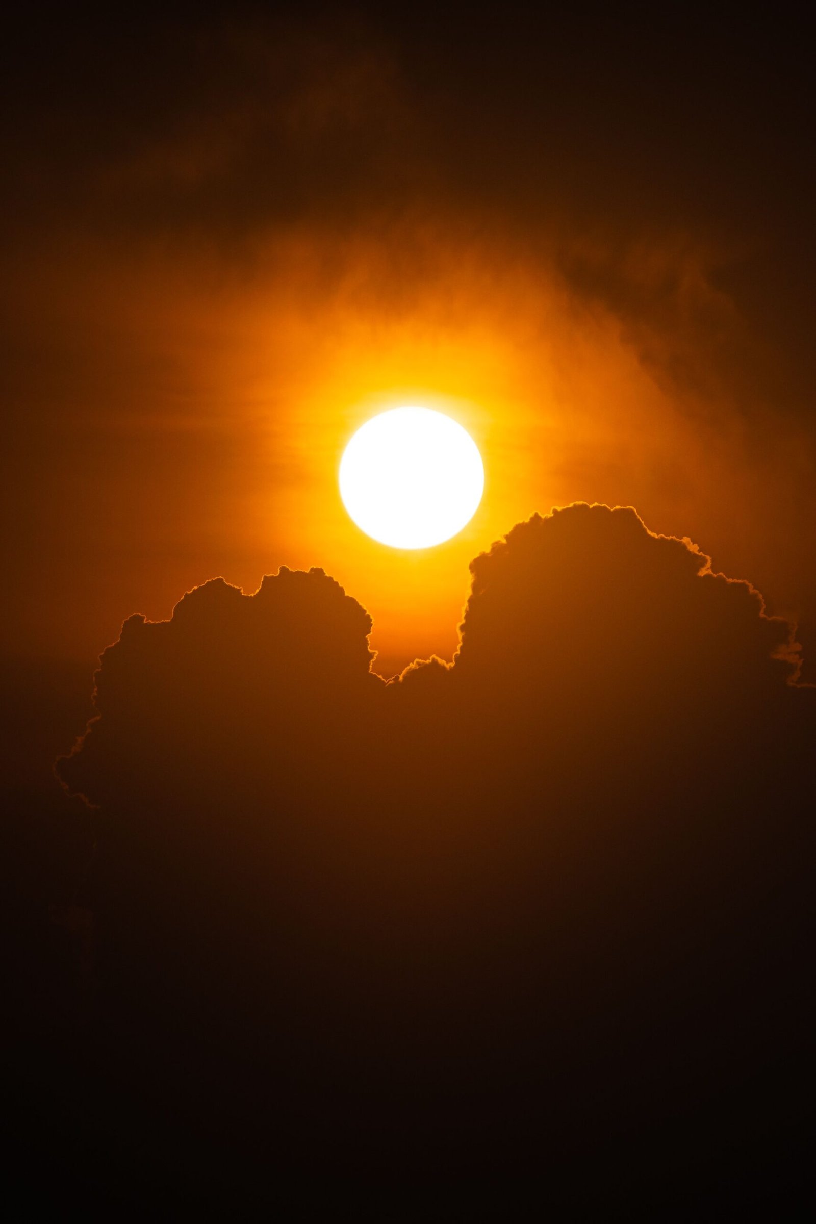 A vibrant sunset with silhouetted clouds creates a dramatic and warm scene in the sky.