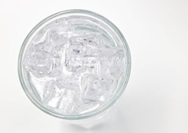 A top view of a glass filled with ice cubes and water, offering a refreshing feel.