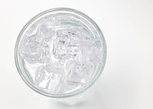 A top view of a glass filled with ice cubes and water, offering a refreshing feel.