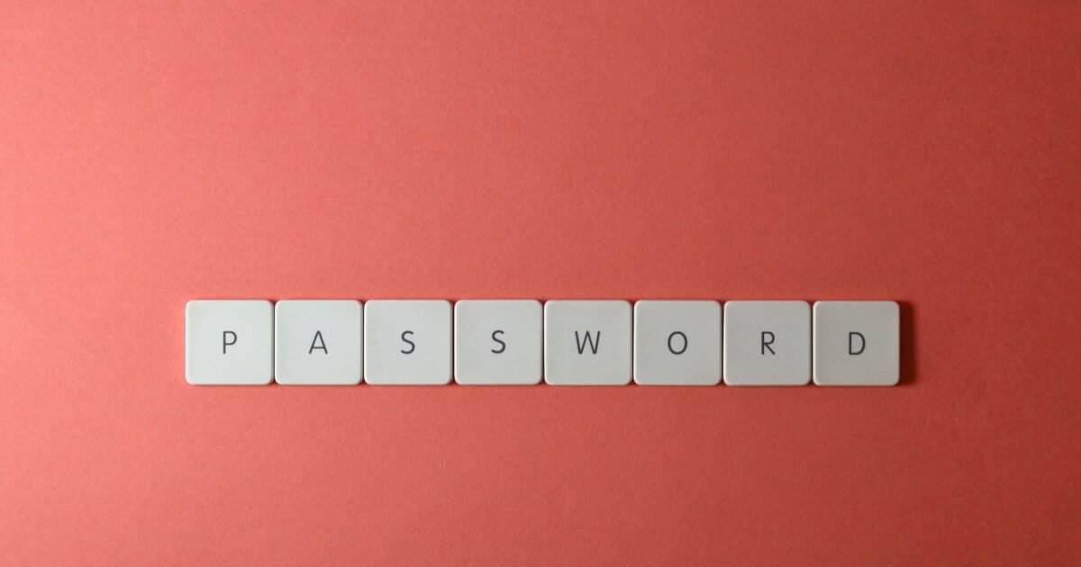 Focus on password security with white keyboard tiles spelling 'PASSWORD' on a coral background.