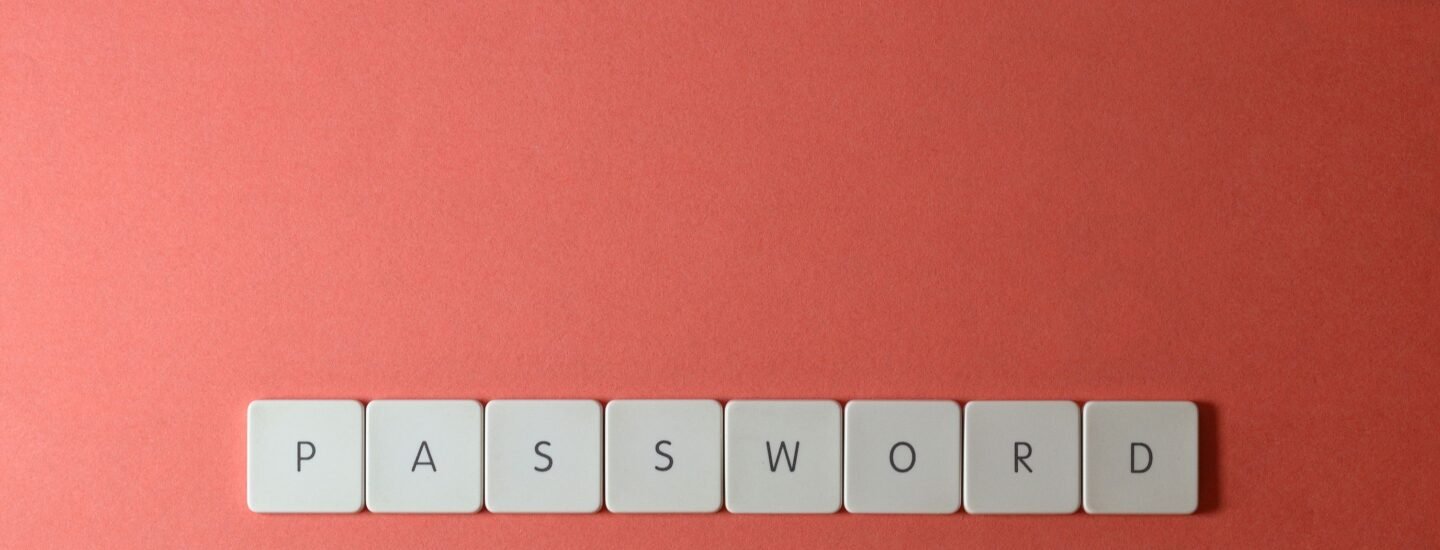 Focus on password security with white keyboard tiles spelling 'PASSWORD' on a coral background.