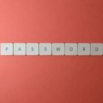 Focus on password security with white keyboard tiles spelling 'PASSWORD' on a coral background.