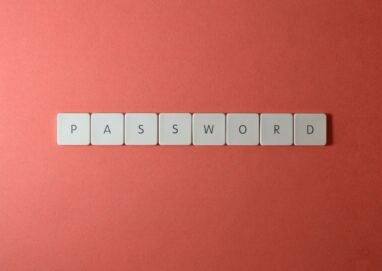 Focus on password security with white keyboard tiles spelling 'PASSWORD' on a coral background.