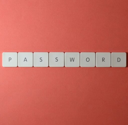 Focus on password security with white keyboard tiles spelling 'PASSWORD' on a coral background.