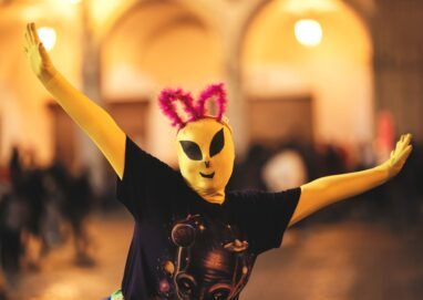 Person in alien costume with quirky ears during a lively Arequipa celebration.