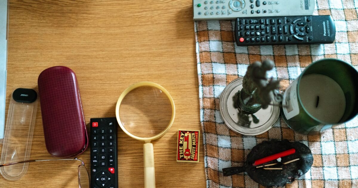 Arrangement of glasses, remote controls, and candle on a table surface.