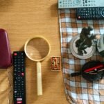 Arrangement of glasses, remote controls, and candle on a table surface.