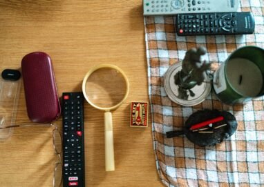 Arrangement of glasses, remote controls, and candle on a table surface.