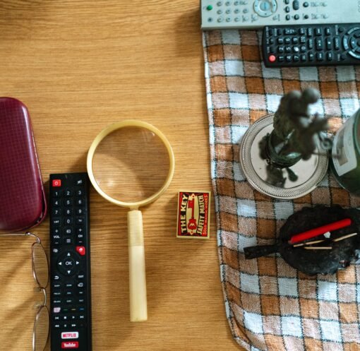Arrangement of glasses, remote controls, and candle on a table surface.