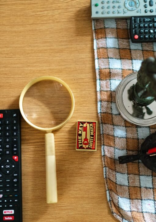 Arrangement of glasses, remote controls, and candle on a table surface.