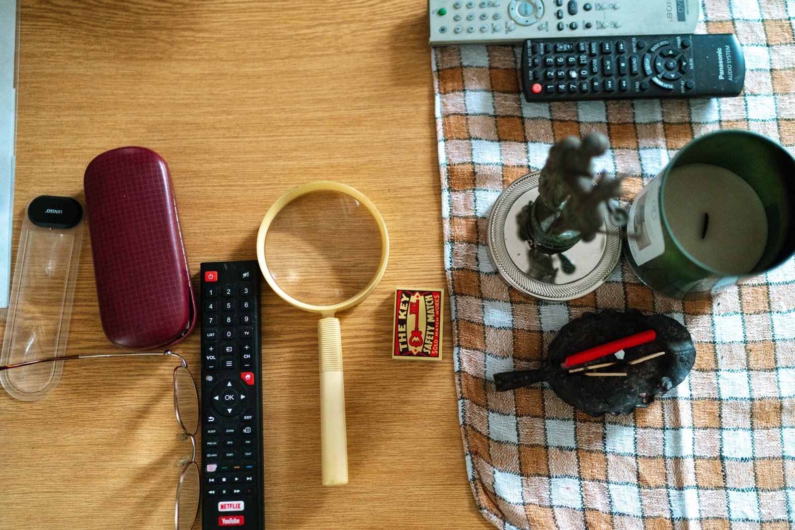 Arrangement of glasses, remote controls, and candle on a table surface.