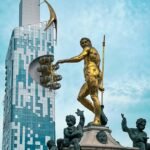 Iconic golden statue with modern skyscraper in Batumi, Georgia's vibrant cityscape.