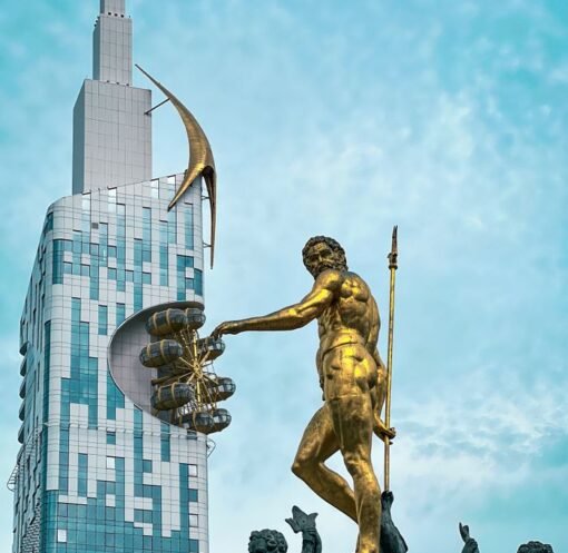 Iconic golden statue with modern skyscraper in Batumi, Georgia's vibrant cityscape.