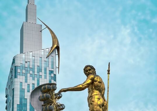 Iconic golden statue with modern skyscraper in Batumi, Georgia's vibrant cityscape.