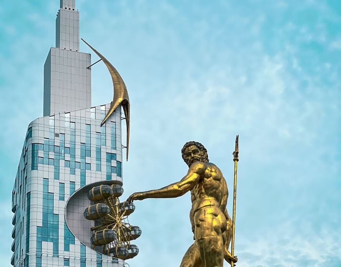 Iconic golden statue with modern skyscraper in Batumi, Georgia's vibrant cityscape.