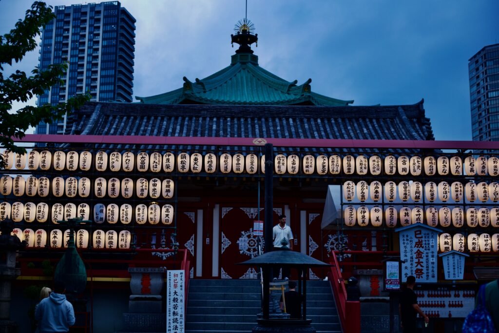 A serene view of a Japanese temple adorned with lanterns during twilight.