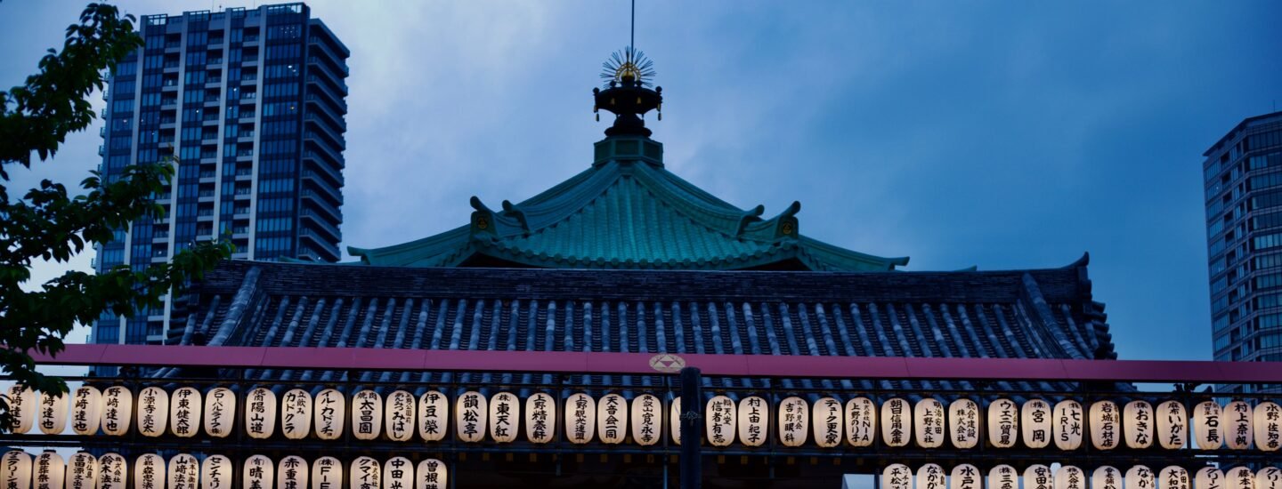 A serene view of a Japanese temple adorned with lanterns during twilight.