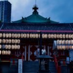 A serene view of a Japanese temple adorned with lanterns during twilight.