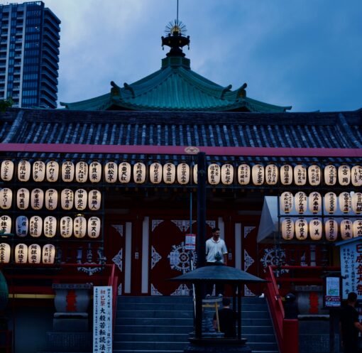 A serene view of a Japanese temple adorned with lanterns during twilight.