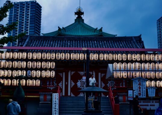 A serene view of a Japanese temple adorned with lanterns during twilight.