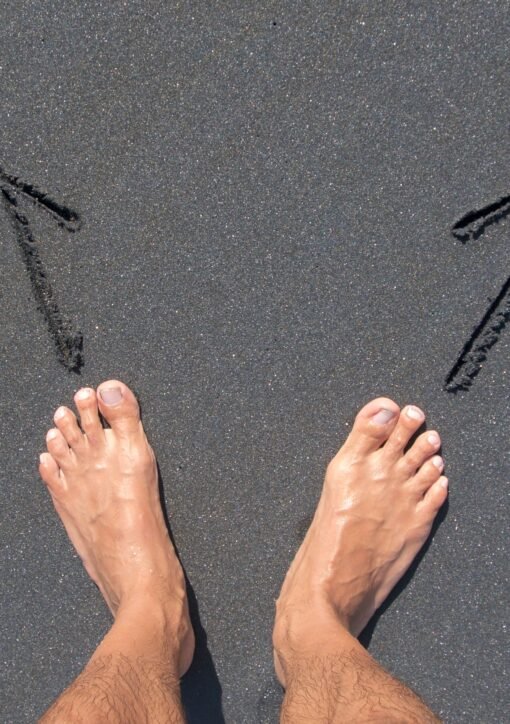 A pair of bare feet on Bali's beach sand with arrows drawn, symbolizing choice and direction.