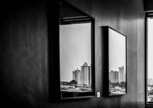 Cityscape reflections captured through indoor mirrors in this monochrome photograph.