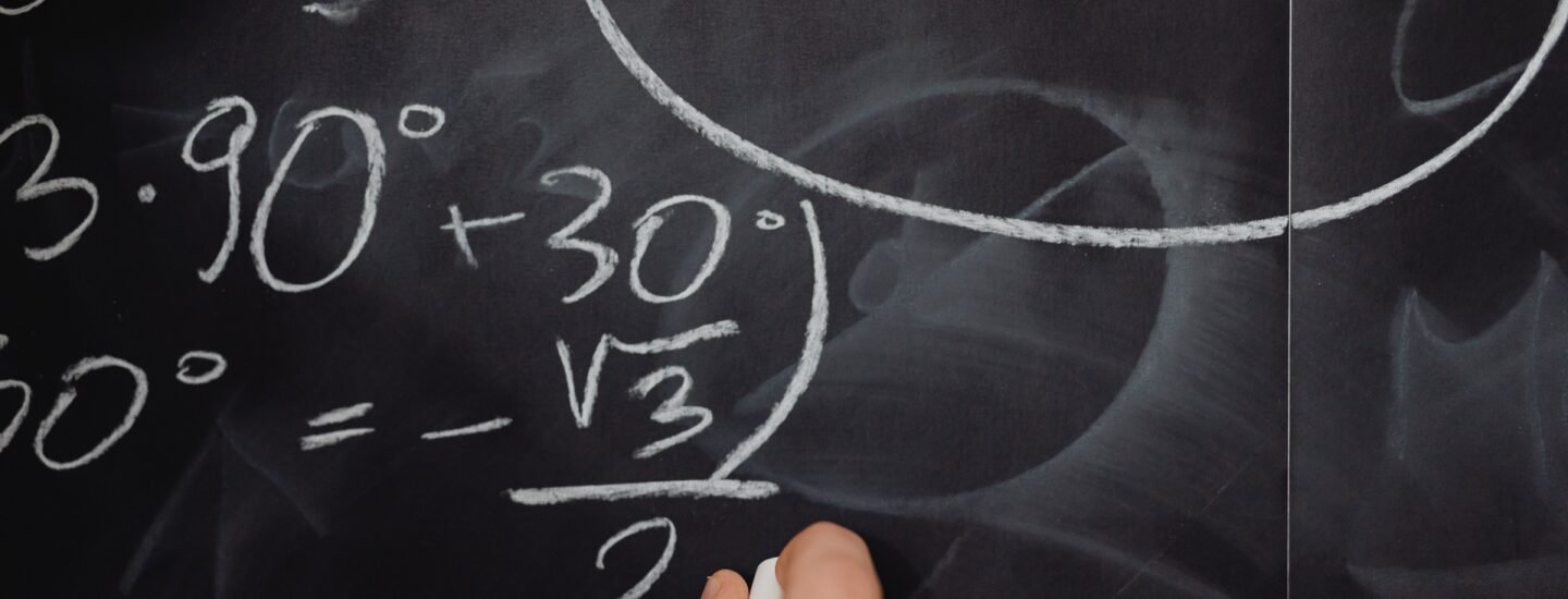 A hand vividly writing complex mathematical equations on a chalkboard.