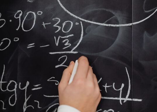 A hand vividly writing complex mathematical equations on a chalkboard.