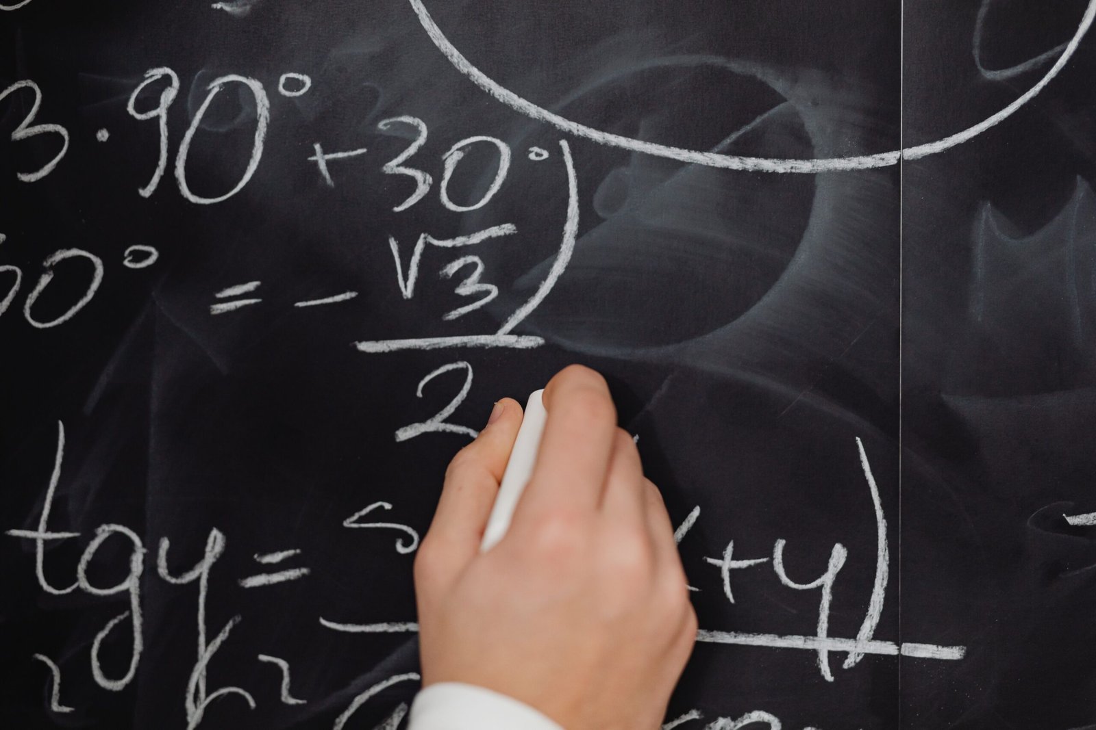 A hand vividly writing complex mathematical equations on a chalkboard.