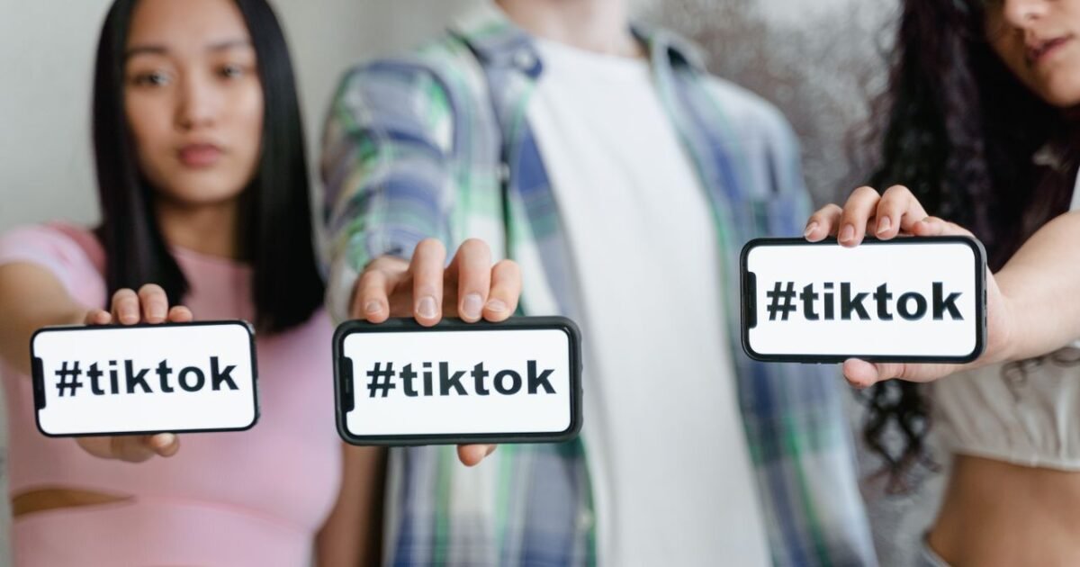 Young adults holding smartphones with TikTok hashtag, showcasing social media engagement.
