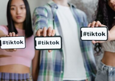 Young adults holding smartphones with TikTok hashtag, showcasing social media engagement.