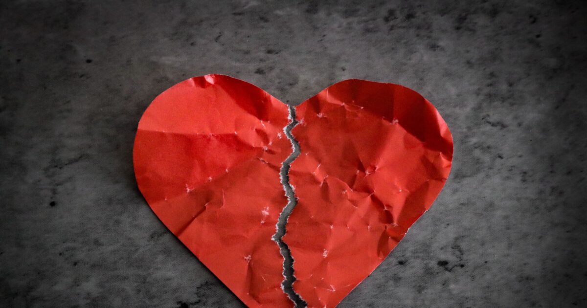 A torn red paper heart symbolizing heartbreak and lost romance.