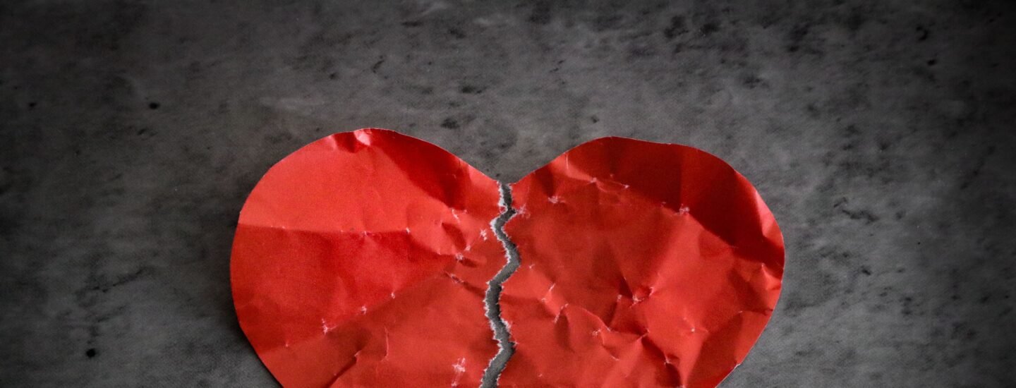 A torn red paper heart symbolizing heartbreak and lost romance.