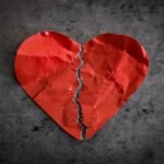 A torn red paper heart symbolizing heartbreak and lost romance.