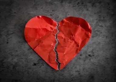A torn red paper heart symbolizing heartbreak and lost romance.