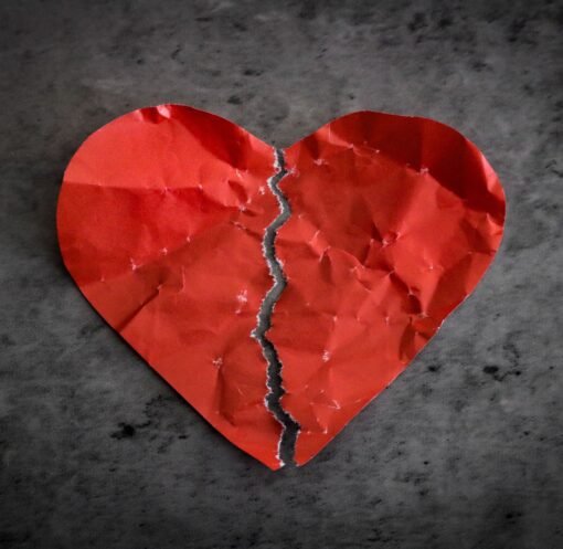 A torn red paper heart symbolizing heartbreak and lost romance.