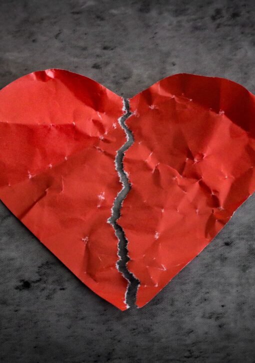 A torn red paper heart symbolizing heartbreak and lost romance.
