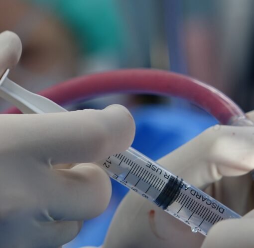 Surgeon's hands handling syringe during a medical procedure in a sterile operating room.