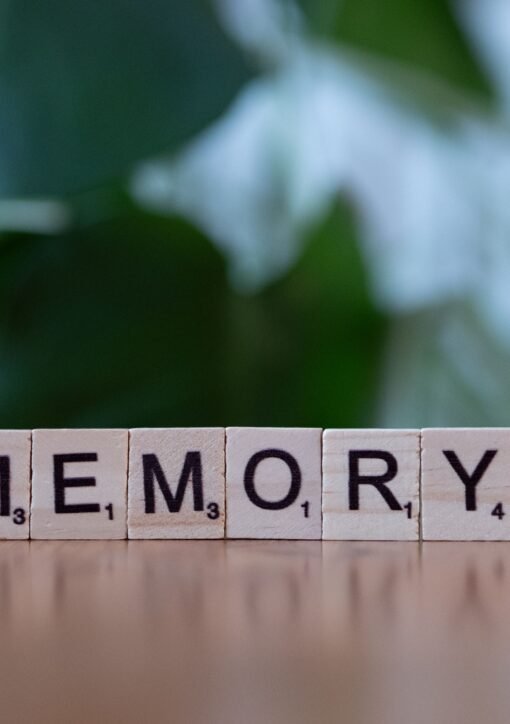 Wooden letter tiles spelling 'Memory' on a wooden table with blurred green background.