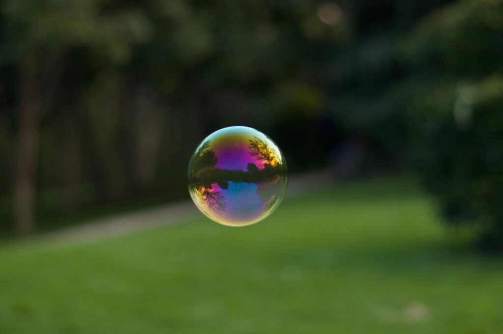 A vibrant soap bubble floating outdoors with a colorful reflection of the surroundings.