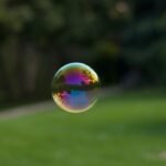 A vibrant soap bubble floating outdoors with a colorful reflection of the surroundings.