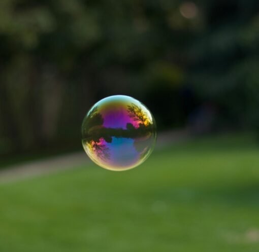 A vibrant soap bubble floating outdoors with a colorful reflection of the surroundings.
