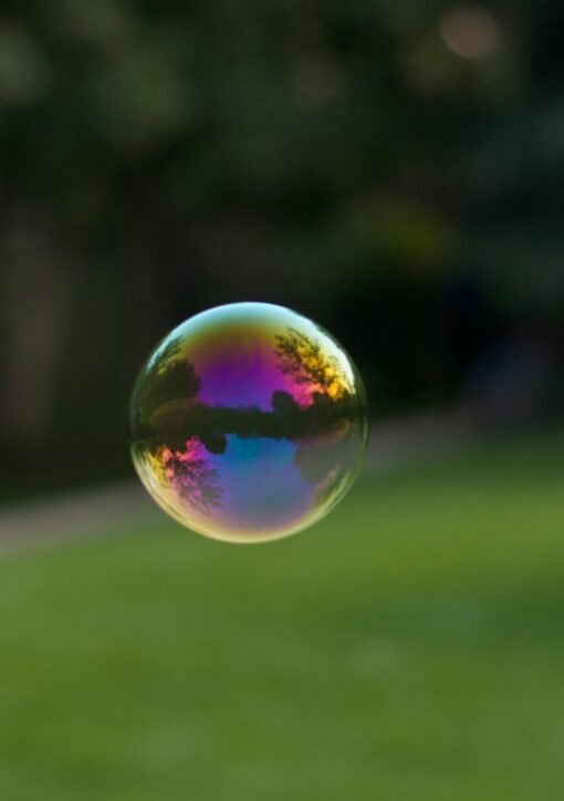 A vibrant soap bubble floating outdoors with a colorful reflection of the surroundings.