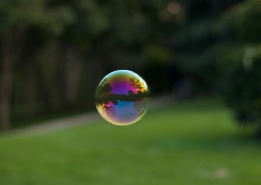 A vibrant soap bubble floating outdoors with a colorful reflection of the surroundings.